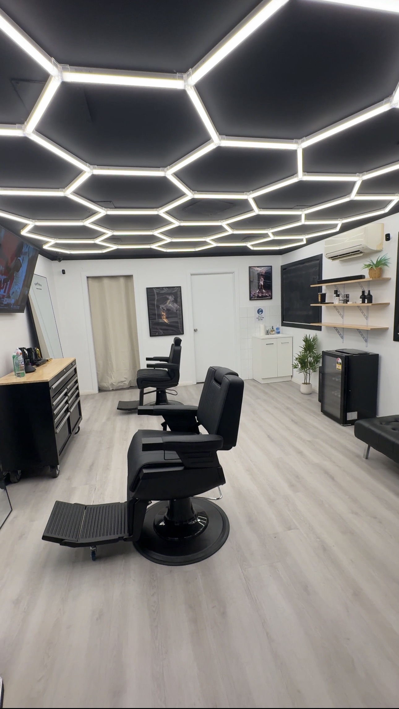 The studio floor at Vision Barber Studio, hexagon lighting above two chairs